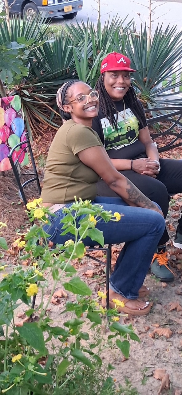 Two community members smiling together in garden setting